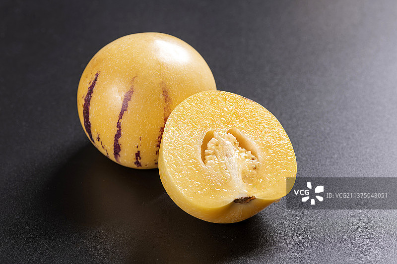 一盘人参果与切片人参果茶水摆放在桌面上特写图片素材