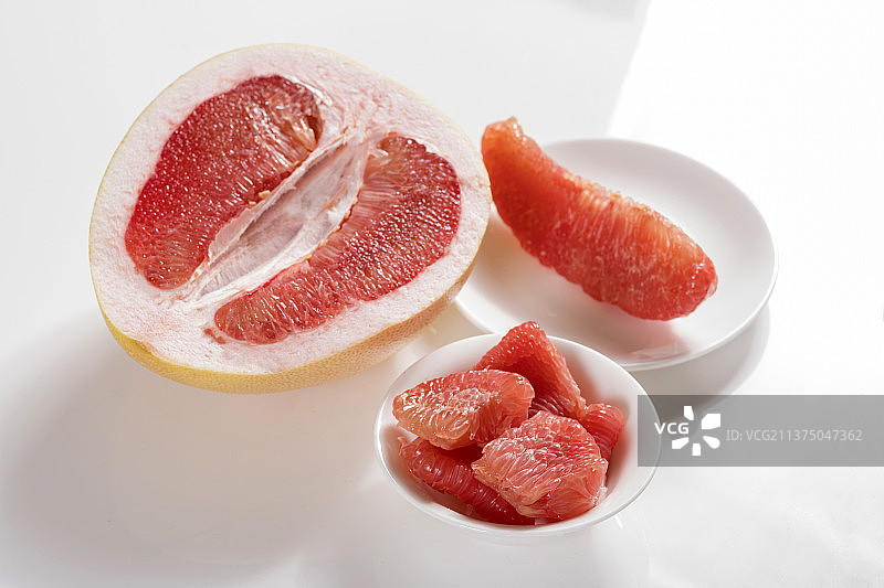 一盘红心柚子和茶水摆放在桌面上图片素材