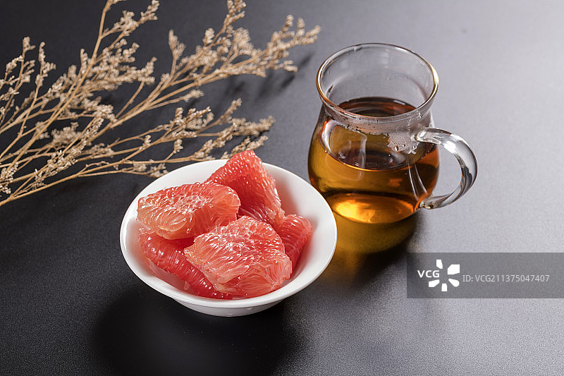 一盘红心柚子和茶水摆放在桌面上图片素材