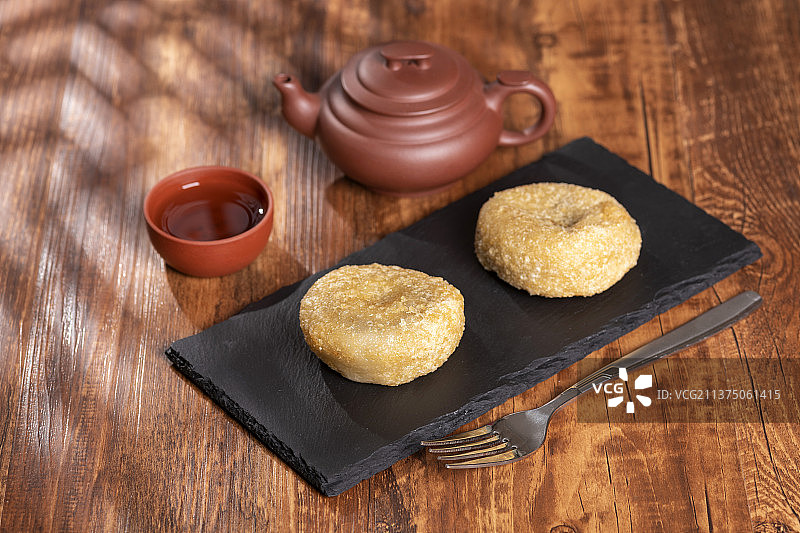 天津小吃炸糕与茶水摆放在木桌面上特写图片素材