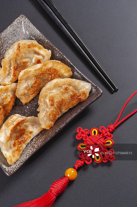 一盘煎饺与醋碟筷子中国结特写黑色背景图片素材
