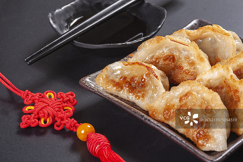 一盘煎饺与醋碟筷子中国结特写黑色背景图片素材