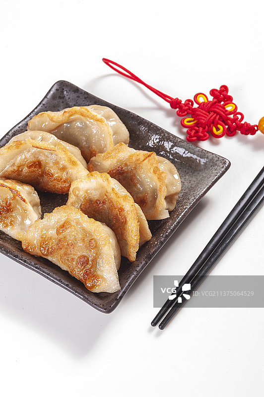 一盘煎饺与醋碟筷子中国结特写黑色背景图片素材