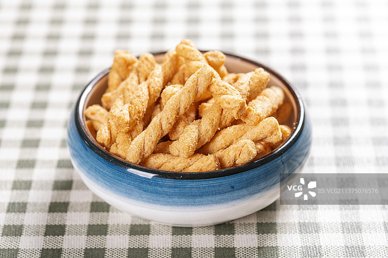 一盘休闲零食小麻花与茶壶茶水摆放在桌面上特写图片素材