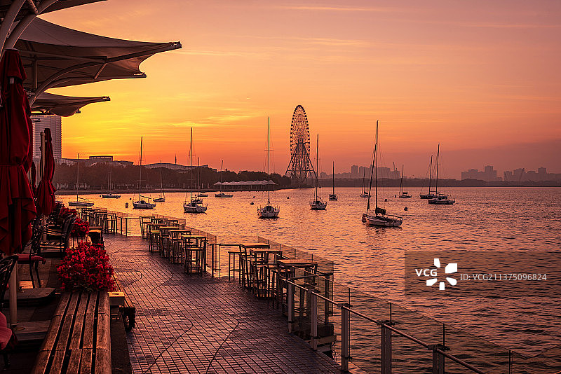 金黄色的日出暖阳中，金鸡湖的游艇码头，游艇和摩天轮都笼罩在金光中图片素材