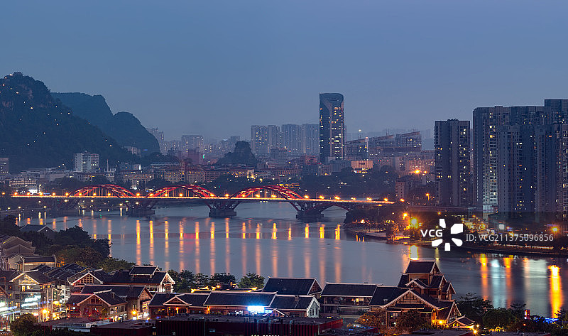 柳州市繁华的夜景，天空深蓝色，近处的窑埠古镇被灯光点亮，远处是文慧桥和马鞍山图片素材