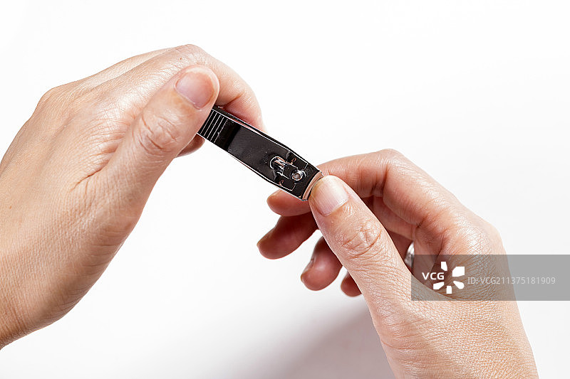 女性手用指甲刀修剪指甲特写白色背景图片素材