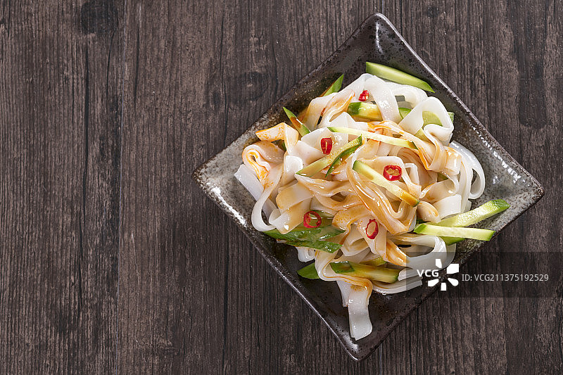 一盘拌凉皮与茶水摆放在桌面上图片素材