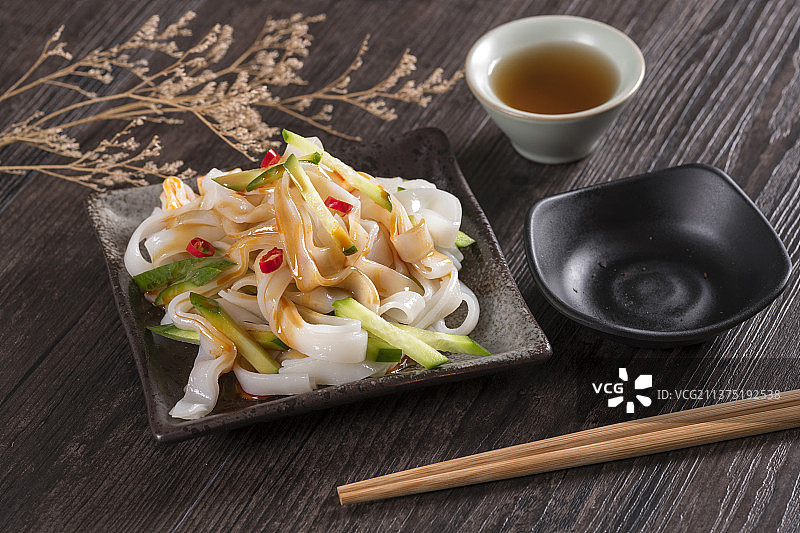 一盘拌凉皮与茶水摆放在桌面上图片素材