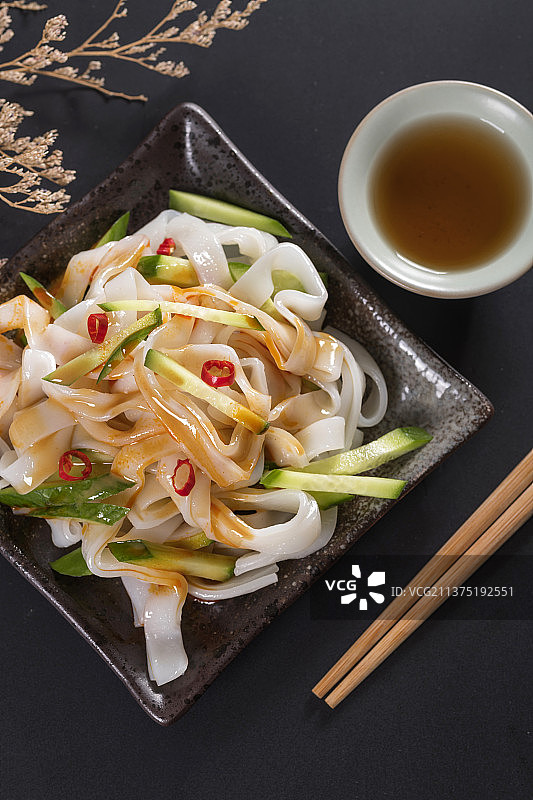 一盘拌凉皮与茶水摆放在桌面上图片素材