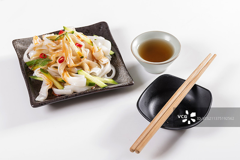 一盘拌凉皮与茶水摆放在桌面上图片素材