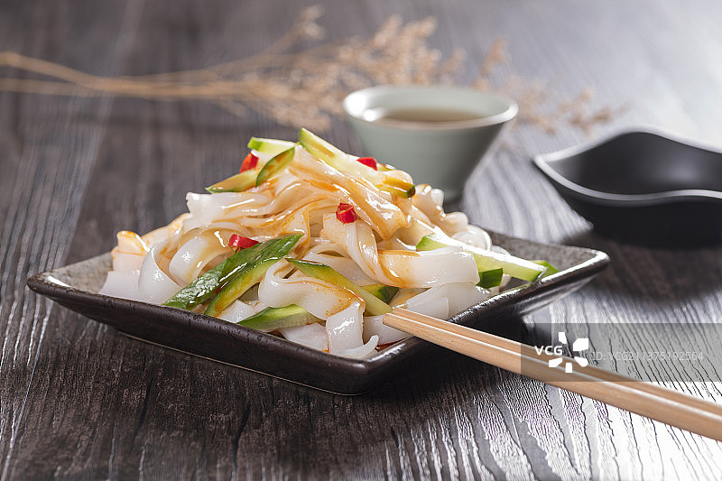 一盘拌凉皮与茶水摆放在桌面上图片素材