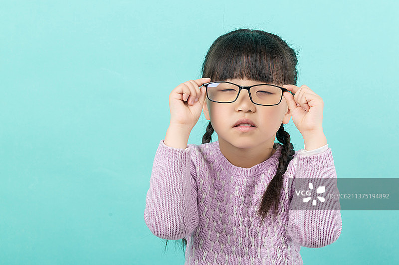 纯色背景前的亚洲小女孩带眼镜图片素材