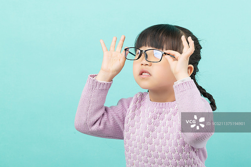 纯色背景前的亚洲小女孩带眼镜图片素材