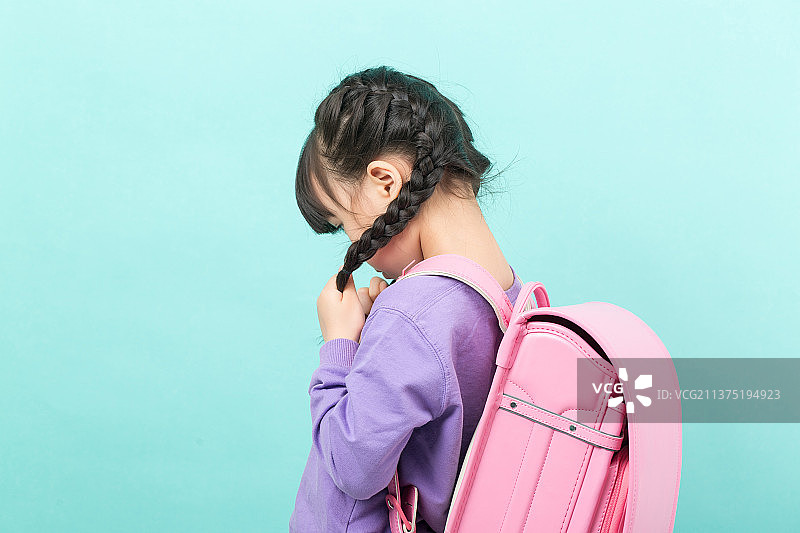 纯色背景前背着书包不开心的亚洲小女孩图片素材