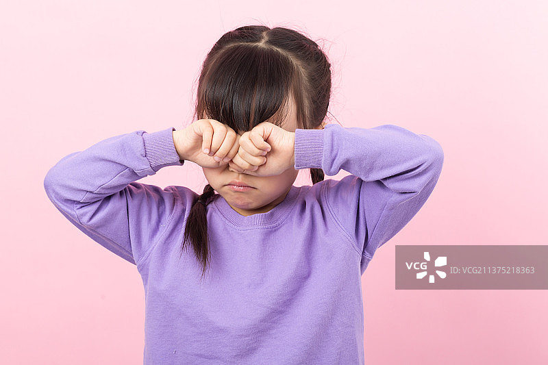 粉色背景前捂着眼睛哭泣的亚洲小女孩图片素材