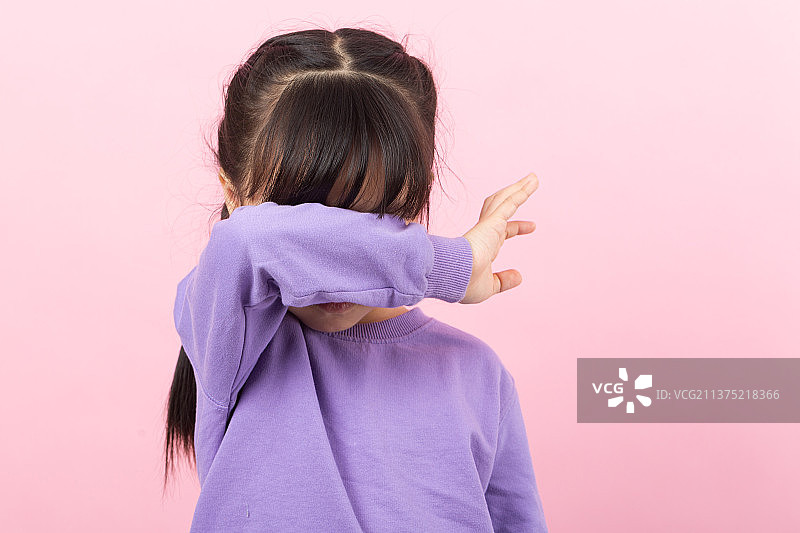粉色背景前捂着眼睛哭泣的亚洲小女孩图片素材