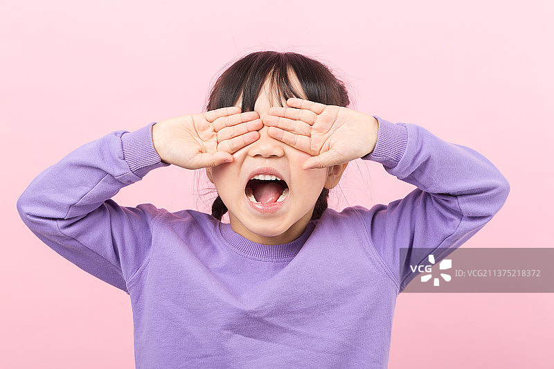 粉色背景前捂着眼睛哭泣的亚洲小女孩图片素材