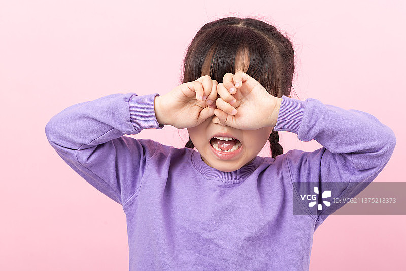 粉色背景前捂着眼睛哭泣的亚洲小女孩图片素材