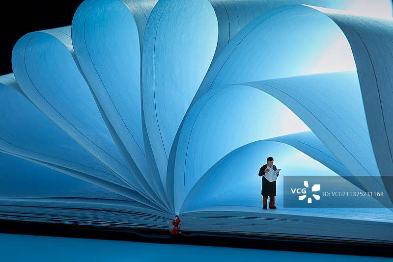 站在书本上看报的男人图片素材