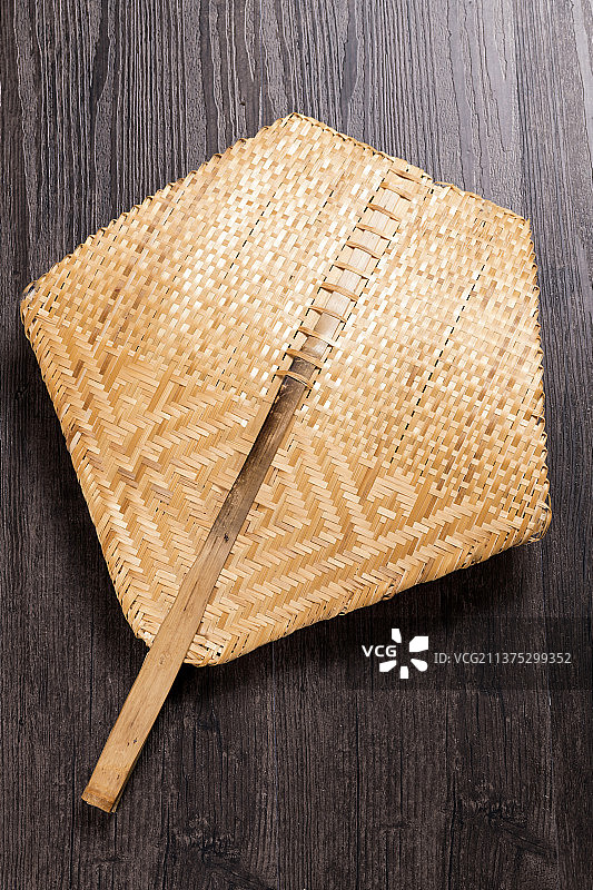 一把竹编扇摆放在木桌面上图片素材