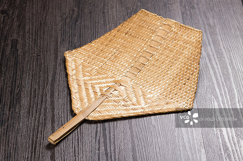 一把竹编扇摆放在木桌面上图片素材