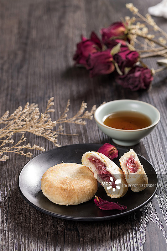 一盘鲜花饼与茶水玫瑰花瓣特写木桌面背景图片素材