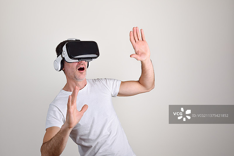 使用VR眼镜的惊讶男人，白色隔离背景图片素材