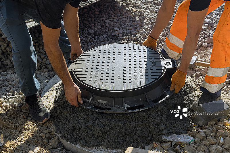 工人安装混凝土化粪池上的污水井盖图片素材