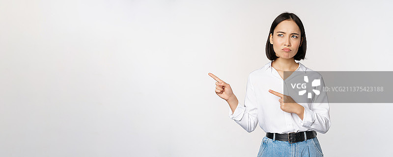 失望的亚洲年轻女性指向左侧图片素材
