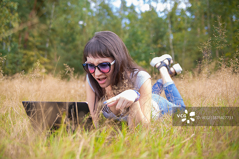 年轻女人在笔记本电脑前情绪激动地打电话图片素材