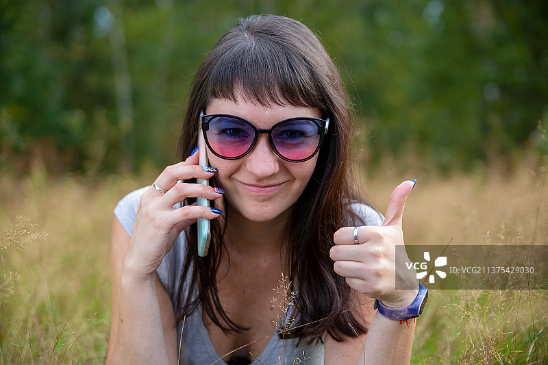 戴眼镜的年轻漂亮女人在打电话微笑图片素材