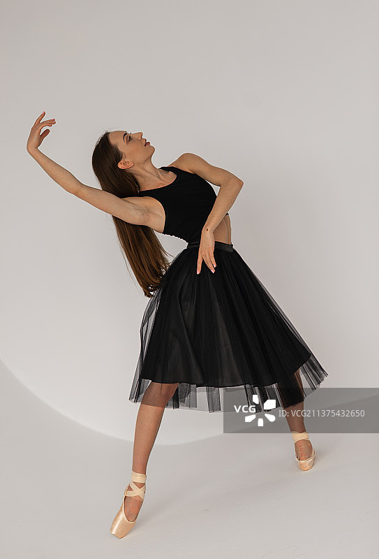 身穿黑色连衣裙在工作室跳舞的美丽芭蕾舞女演员，正在训练图片素材