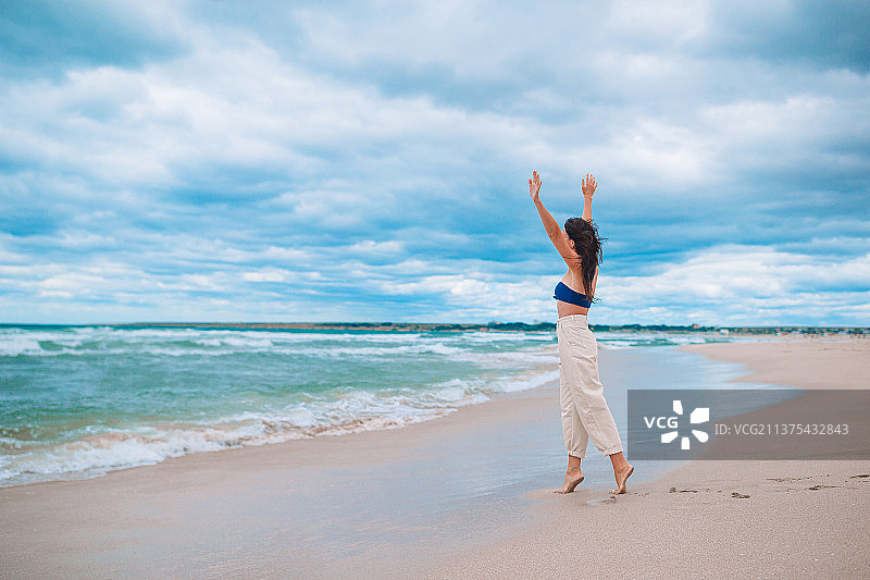 年轻女人在暴风雨中的海滩上图片素材