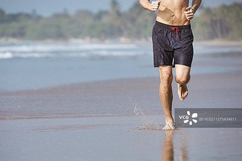 男人在沙滩上跑步，低视角图片素材