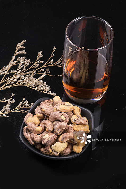 一盘腰果洋酒茶水摆放在桌面上特写图片素材