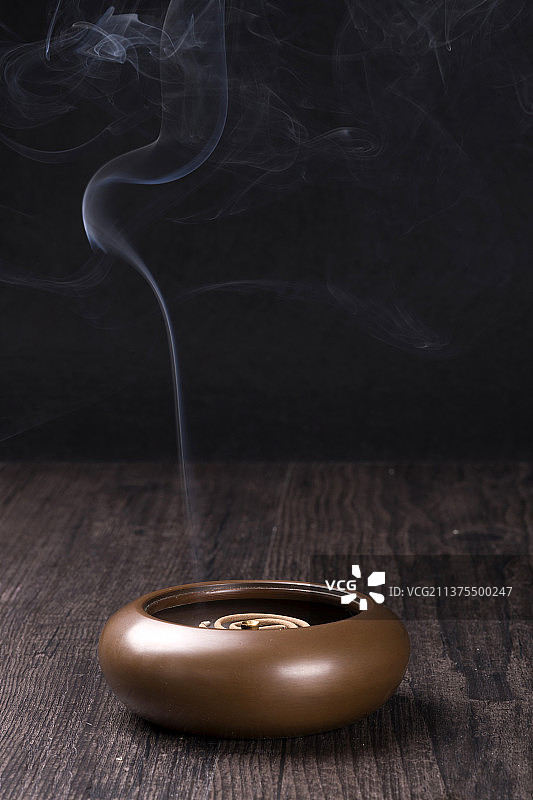 正在焚香的紫铜香炉摆放在木桌面上图片素材