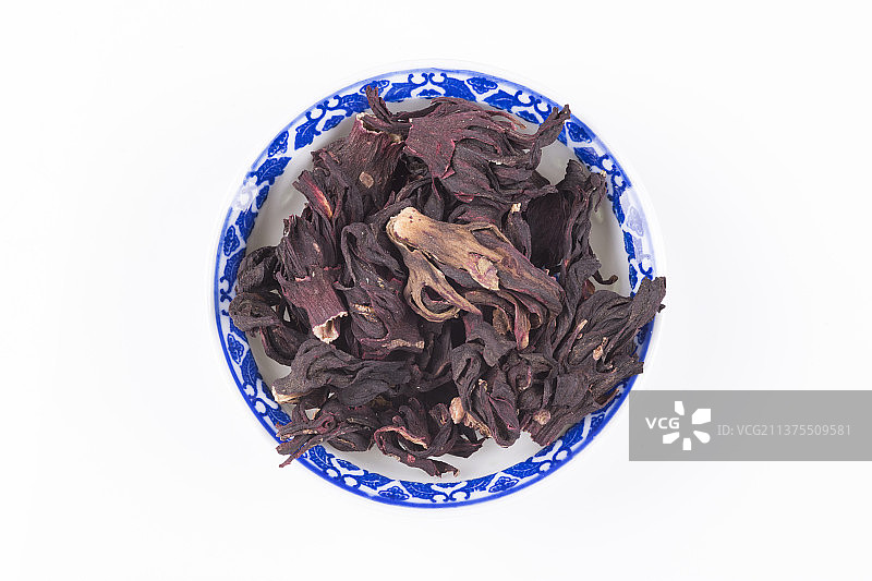 一盘玫瑰茄与一杯玫瑰茄茶摆放在桌面上特写图片素材