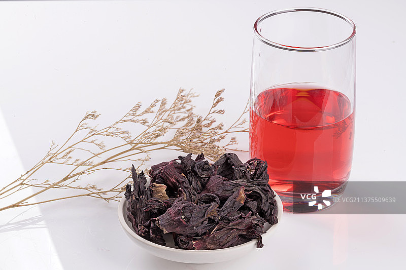 一盘玫瑰茄与一杯玫瑰茄茶摆放在桌面上特写图片素材