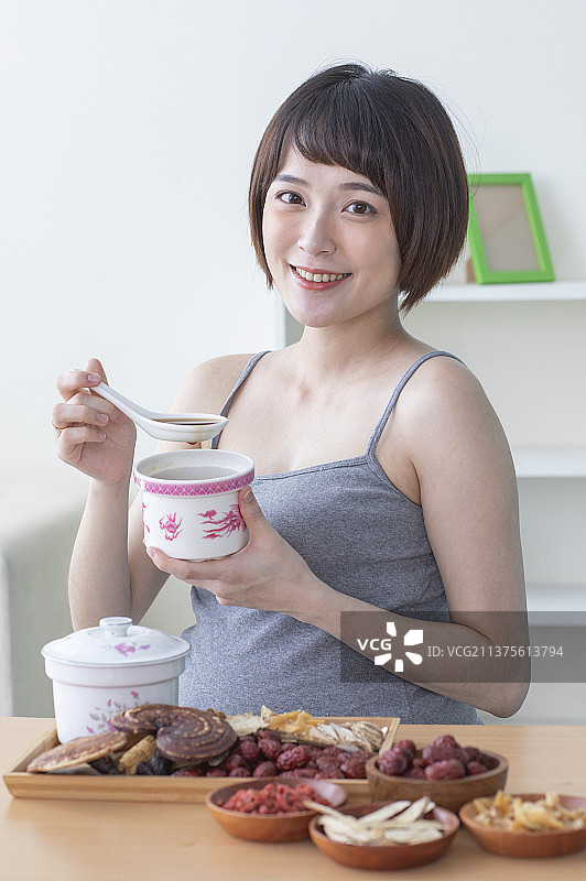 孕妇拿着汤匙正在喝中药补汤图片素材
