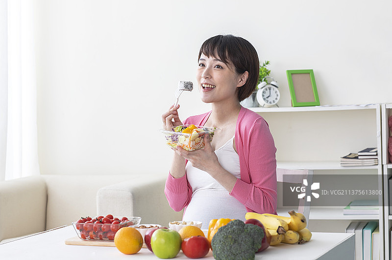 孕妇正坐着在吃水果色拉图片素材