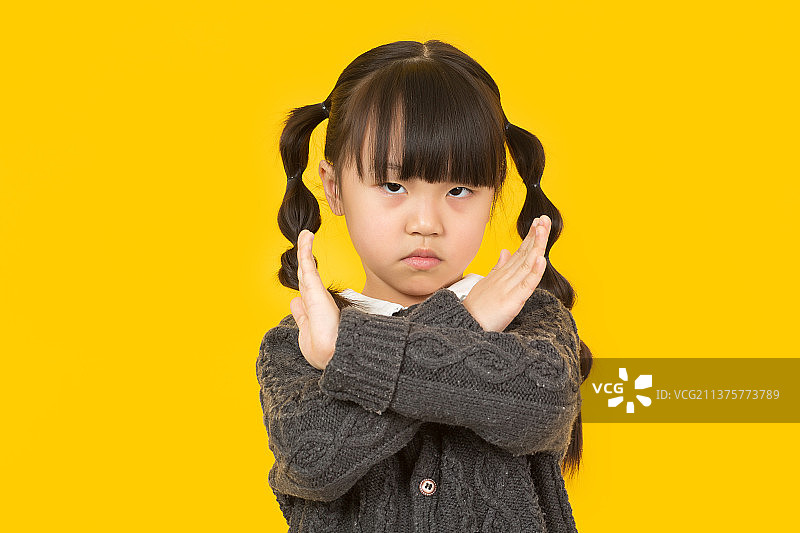 暖黄色背景前的女孩做手势拒绝图片素材