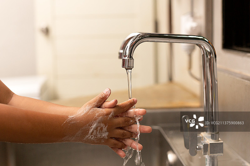 泰国儿童在水龙头下用洗手液洗手图片素材