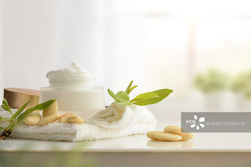 浴室白色桌子上含杏仁提取物的保湿霜图片素材