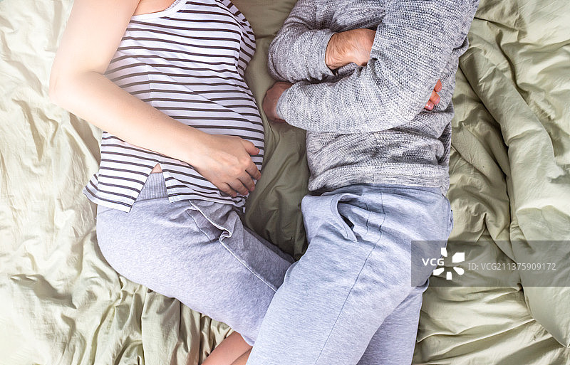 孕妇和男子在床上，阳光照射的俯视图图片素材