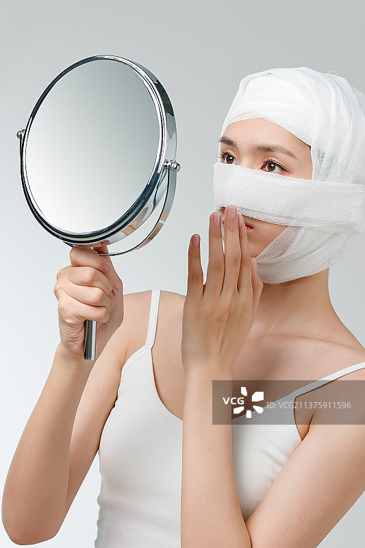 做整形手术的青年女人照镜子图片素材
