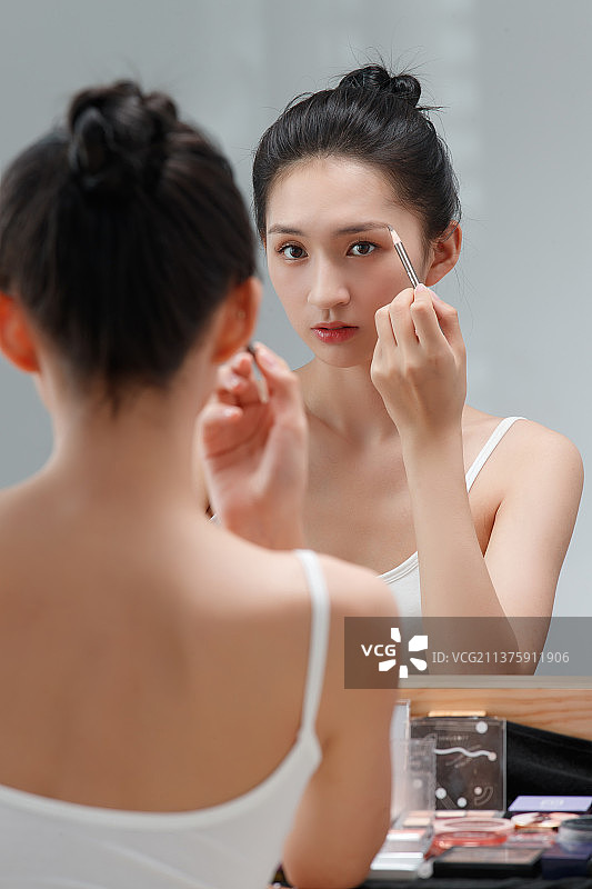 年轻女人对着镜子化妆图片素材