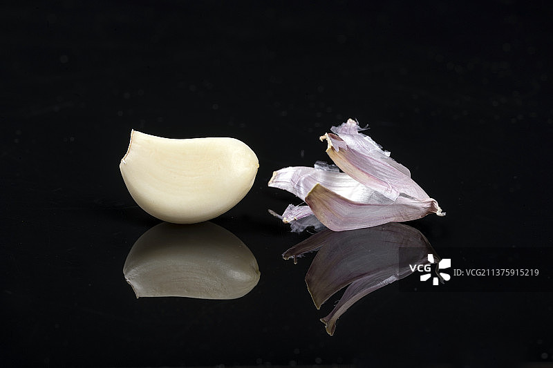 一簸箕大蒜摆放在黑色背景上图片素材