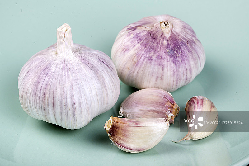 一簸箕大蒜摆放在黑色背景上图片素材