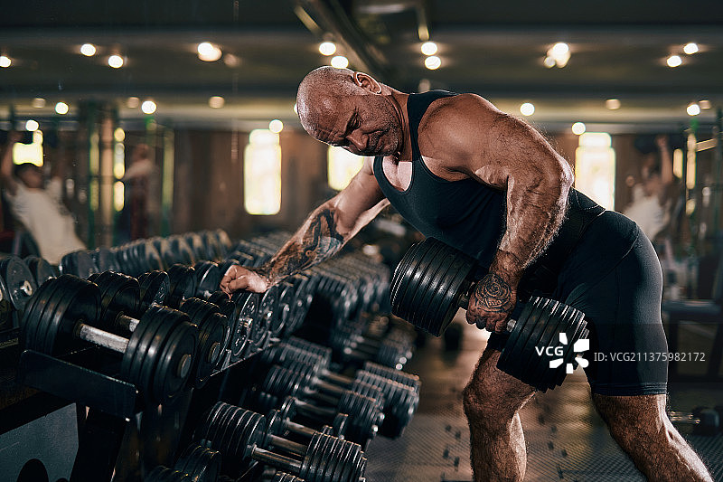 年长的男人在明亮的工作室健身房进行高强度锻炼图片素材